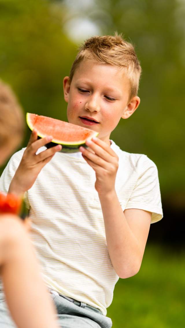 Tre damer spiser og drikker mat ved et bord utendørs