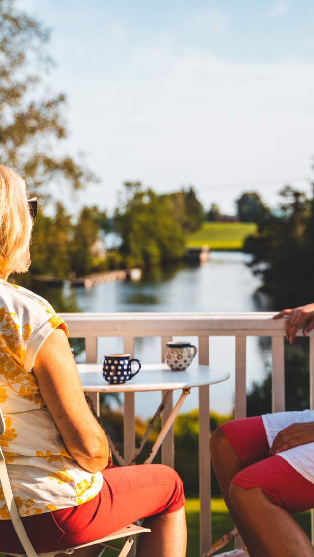 Tre damer nyter en kaffepause i kveldssola i Strømsfossen, Aremark