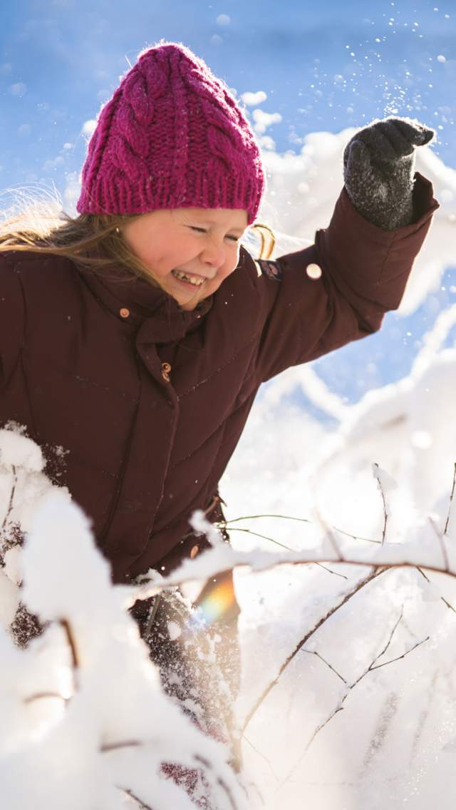 Jente som kommer gjennom snøbelagte busker