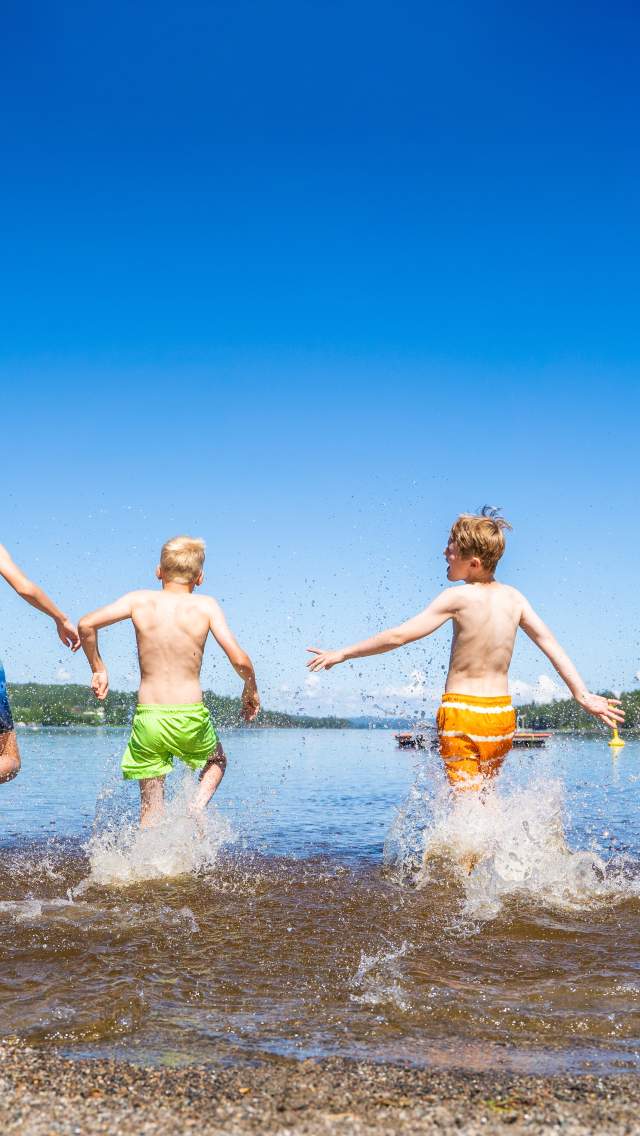 4 guys in colorful shorts running into the water