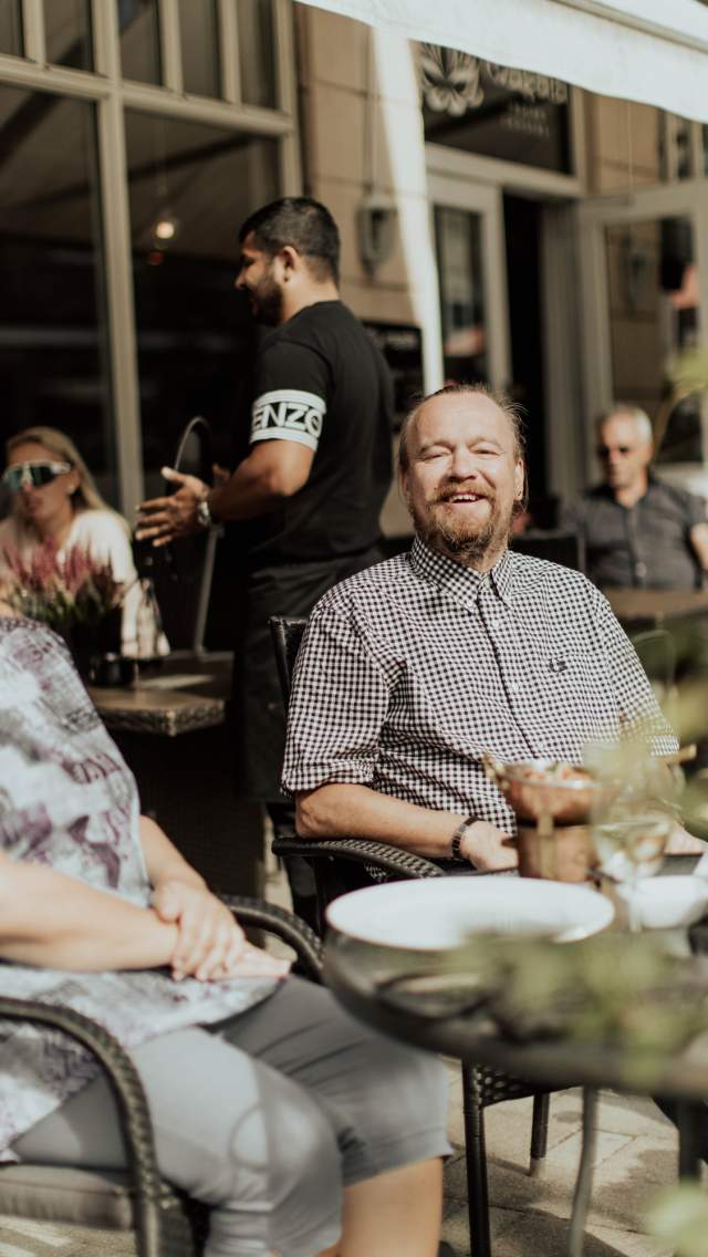 Smilende mennesker som koser seg på en uteservering i Sarpsborg sentrum. Foto.
