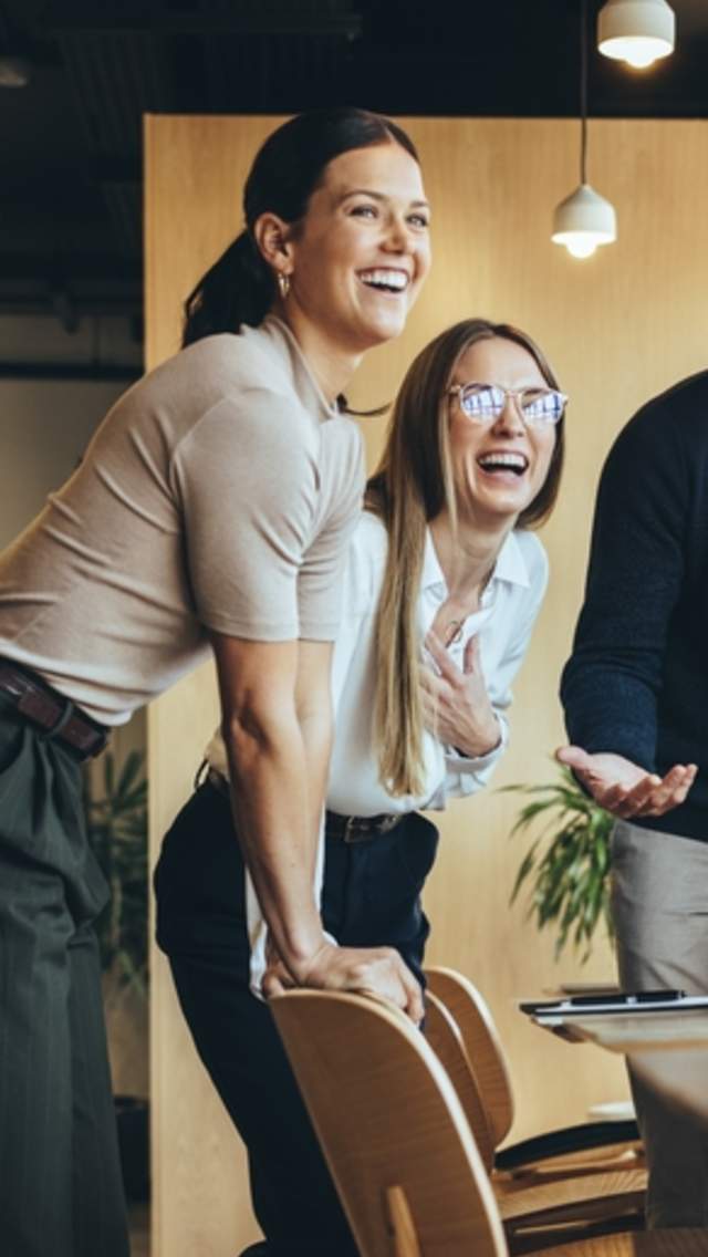 En gruppe kolleger jobber sammen på et prosjekt mens de smiler og ler