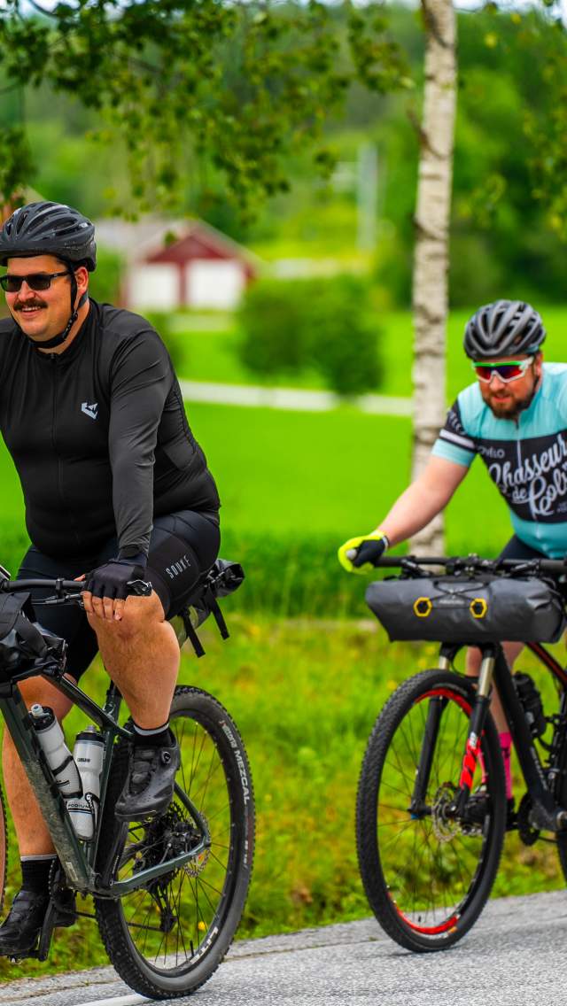 Syklister sykler gjennom frodig landskap