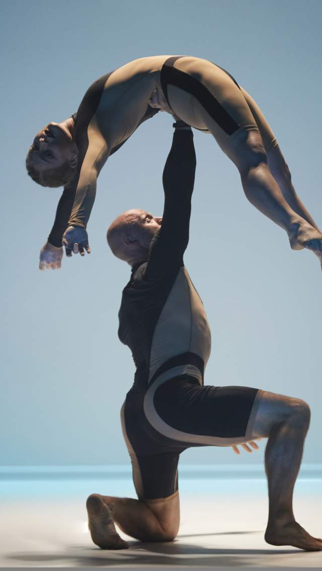 Image shows two Circa acrobats performing a lift on a blue background.