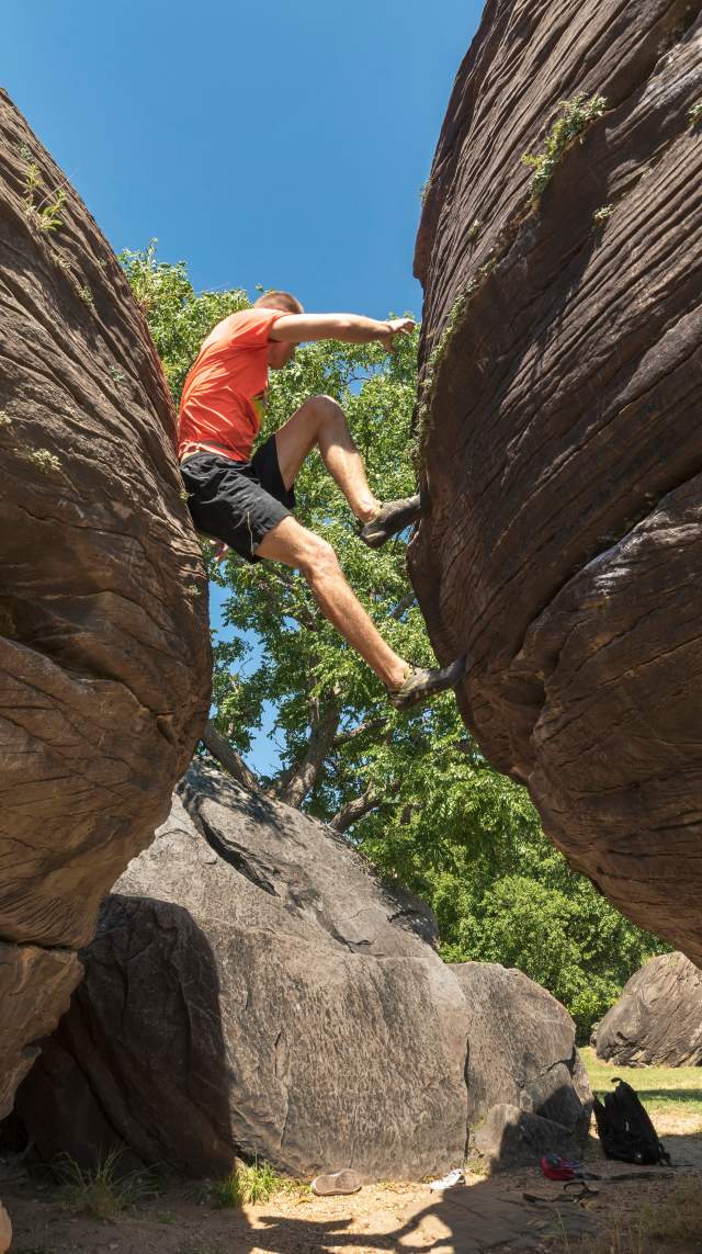 A person climbs between two rocks in Rock City