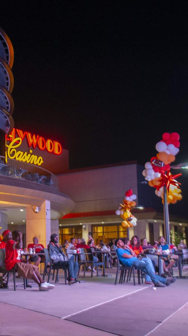Crowd gathers outside Hollywood Casino with colorful lights lighting the area