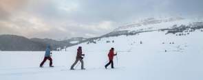 Three people cross-country skiing across a frozen lake with Absoroka Mountains in the background, Park County.