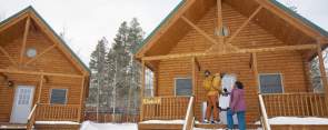 two people standing on a snowy porch in front of a cabin