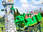 Guests ride a Lego dragon coaster by a tower