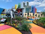 A giant Monopoly dog and Scrabble tile pieces spelling out the word "Play" stand in the winding Hasbro Game Park at the Strong National Museum of Play