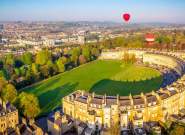 An aerial view of the Royal Crescent in Bath near Bristol, with hot air balloons launching from the green