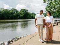 a man and woman walk along a riverside path