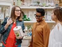 three women admire a white floral canister