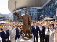 men pose beside statue at Bridgestone Arena