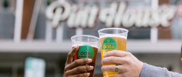 Two DORA cups cheersing in front of Urban's Pint House