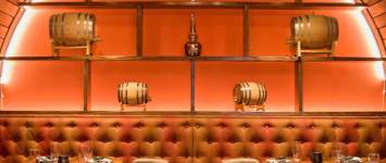Song Lan's private dining room featuring a cozy, dimly lit booth with orange walls, wooden accents, and upholstered seating.