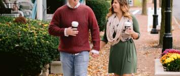 A couple walking hand in hand with coffee cups through the leaf covered, bricked lined streets of Historic Dublin in the fall.