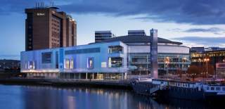 Photo of the waterfront hall in Belfast overlooking the water with the Hilton hotel in the background.