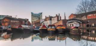 Canal boats moored at Gas Street Basin Birmingham in front of bring building a a large cubed glass building behind