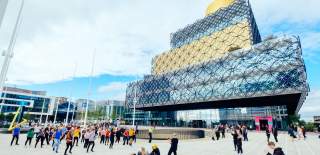 A group of people standing in Centenary Square in front of the Library of Birmingham