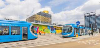 Two blue West Midlands trams outside of Birmingham library