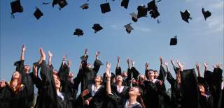 A group of people wearing caps and gowns throwing their caps in the air - Credit Visit West