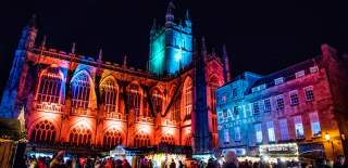 Bath Abbey lit up in various colours for the Bath Christmas Market