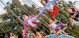 Children riding on a swing ride at Bristol International Balloon Fiesta - Credit Paul Box