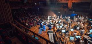 An orchestra performing on the stage inside the Beacon Hall at Bristol Beacon - credit Shotaway