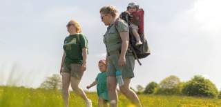 Two adults and two children walking through a field at Dyrham Park