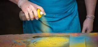 A person spraying a paint can onto a canvas at Graft Bristol - credit Yuup
