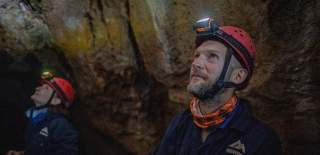 Two people looking above in a cave
