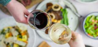 Red and white glass of wine being held above some food