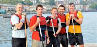 A group of men holding paddles while standing on the bank at Bristol's Harbourside - credit Adventurous Activity Company