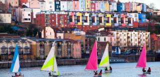 A view of small sailboats on Bristol's Harbourside with the colourful houses of Cliftonwood in the background - credit Paul Box