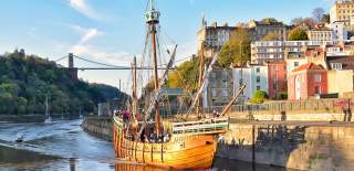 A view of The Matthew replica ship passing through Bristol's Cumberland Basin with the Clifton Suspension Bridge in the background - credit Nick Greville