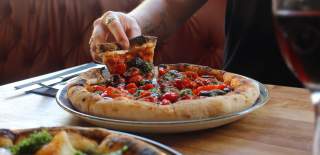 Person pulling a slice of vegan pizza - credit Cafe Napolita