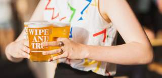 A woman carrying two pints of beer at the Wiper & True Taproom in East Bristol - credit Wiper and True