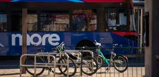 Blue bus in front cycles leaning on railings