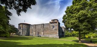 Colchester Castle, surrounded by green trees and grass.