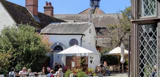 Image shows a timber framed building with a beautiful outside garden