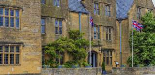 The honey-coloured Lygon Arms Hotel, in the Cotswolds, draped in wisteria with Union Jack flags flying