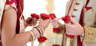 A bride and groom hold flower garlands