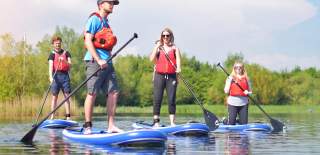 A group of people paddleboard on a lake at Cotswold Lakes