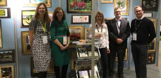 A group of people smile in front of the Cotswolds stand at a show