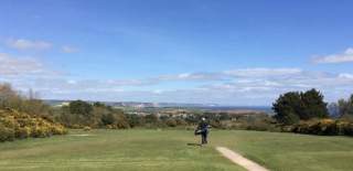 golf course and a golfer walking away sea view landscape in a disctance