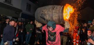 man carrying a barrel which is on fire