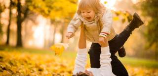 mother and child playing in leaves in autumn