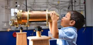 Child looking through an old telescope