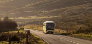 A beige coloured coach travelling through Devon
